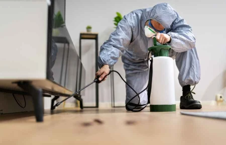 Licensed Conroe TX pest control technician applying termite treatment along an interior floor
