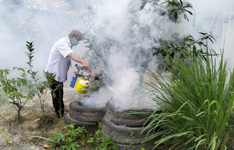 Pest control technician fogging stacked tires holding standing water, a common mosquito breeding source in Conroe, TX yards