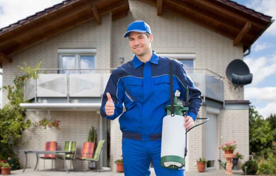 Pest control technician giving a thumbs up outside a Conroe, TX home after a professional treatment