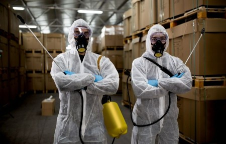 Two licensed pest control technicians in full protective gear preparing for bed bug treatment in a Conroe, TX property