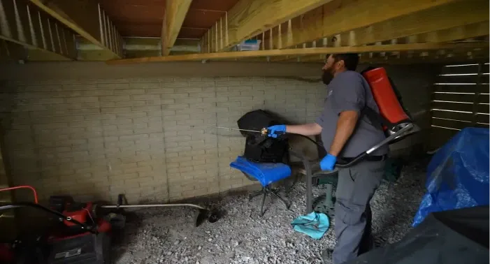 Home 2 Licensed Conroe TX pest control technician treating termite entry points along a home foundation